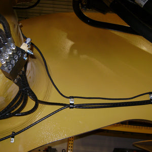Loader arm lube block mounted behind cross-member to protect from damage
